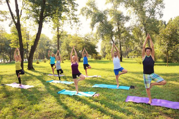 Group of young people practicing yoga in park